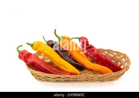 Peperoni colorati chiamati corna di bue nel cestino di vimini isolato su bianco, spazio copia Foto Stock