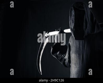 Morte tenendo una vecchia lama affilata scythe sulle spalle della morte nel buio paura e terrore Foto Stock