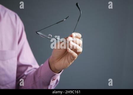 Primo piano della mano dell'uomo che tiene vecchio eyeglass Foto Stock