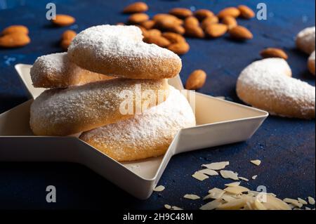 Macaroni alla vaniglia a forma di mezzaluna in zucchero a velo su sfondo blu Foto Stock
