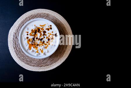 Manti turchi con pepe rosso, salsa di pomodori, yogurt e menta, ravioli turchi in piatto bianco su sfondo nero isolato Foto Stock