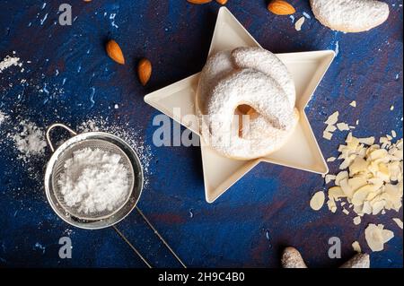 Macaroni alla vaniglia a forma di mezzaluna in zucchero a velo su sfondo blu Foto Stock