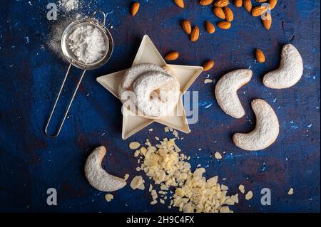 Macaroni alla vaniglia a forma di mezzaluna in zucchero a velo su sfondo blu Foto Stock