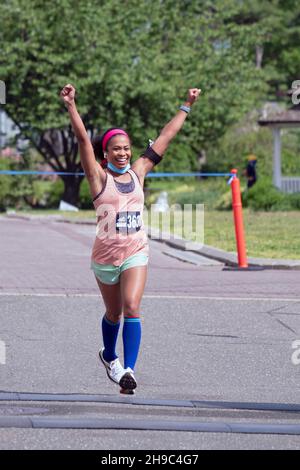 Una giovane donna si è giubilata mentre si avvicina al traguardo della mezza maratona delle regine di NYCRuns nel Flushing Meadows Corona Park a New York City. Foto Stock