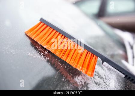 Problemi invernali con la vettura. Un uomo pulisce l'auto dalla neve con una spazzola Foto Stock