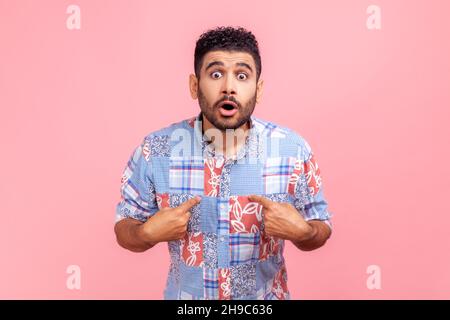 WOW, sono io. Uomo stordito che indossa una maglietta casual blu che stupisce la fotocamera e si punta, scioccato da un successo improvviso. Studio interno girato isolato su sfondo rosa. Foto Stock