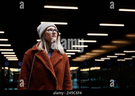 Ritratto di bella donna in occhiali. Donna che indossa un cappotto in città. Passeggiata in strada Foto Stock