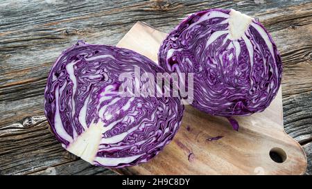 Cavolo rosso tagliato a metà su tagliere su vecchia tavola di legno resistente agli agenti atmosferici Foto Stock