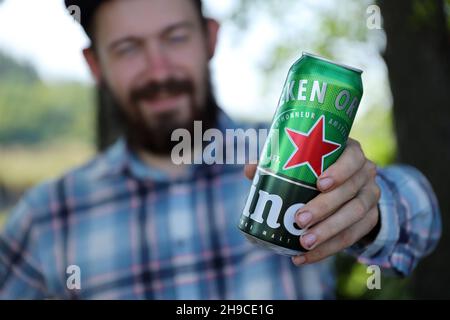 KHARKOV, UCRAINA - 31 LUGLIO 2021: Uomo con lattina verde di birra chiara di Heineken prodotta dalla birreria olandese Heineken N.V. Foto Stock