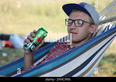 KHARKOV, UCRAINA - 31 LUGLIO 2021: Uomo con lattina verde di birra chiara di Heineken prodotta dalla birreria olandese Heineken N.V. Foto Stock