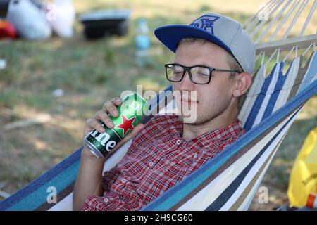 KHARKOV, UCRAINA - 31 LUGLIO 2021: Uomo con lattina verde di birra chiara di Heineken prodotta dalla birreria olandese Heineken N.V. Foto Stock