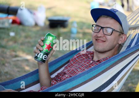 KHARKOV, UCRAINA - 31 LUGLIO 2021: Uomo con lattina verde di birra chiara di Heineken prodotta dalla birreria olandese Heineken N.V. Foto Stock