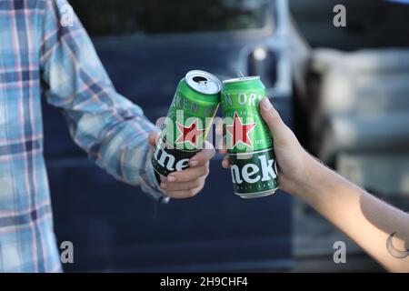 KHARKOV, UCRAINA - 31 LUGLIO 2021: Lattine di Heineken birra lager pallido nelle mani degli uomini all'aperto Foto Stock