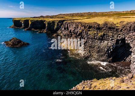 Le scogliere e una grotta nelle scogliere di Arnarstapi, Penisola di Snaefellsnes, Islanda Foto Stock