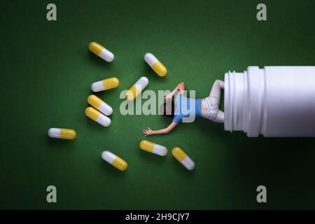 Una donna esce da un vaso di medicina. Le capsule di farmaco sono sparse sul pavimento. Tossicodipendenza. Foto Stock