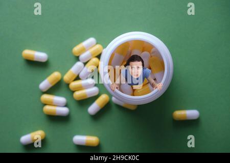 Una donna esce da un vaso di medicina. Le capsule di farmaco sono sparse sul pavimento. Tossicodipendenza. Foto Stock