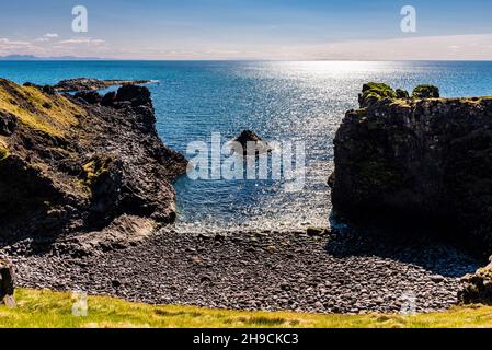 Una baia e rocce alle scogliere di Arnarstapi, Penisola di Snaefellsnes, Islanda Foto Stock