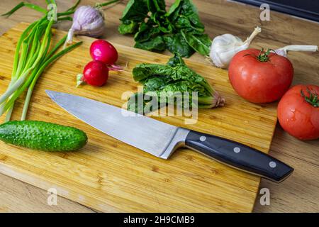 Verdure appena raccolte. Pomodori, cetrioli, peperoni, prezzemolo, zucchine, porri, aglio spinaci cipolline verdi sul tavolo vicino serra Foto Stock