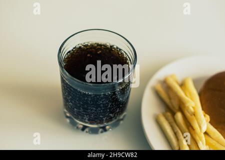 Patatine fritte nel piatto bianco con susa e soda in bicchiere Foto Stock