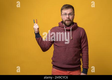 L'uomo soddisfatto e attraente tiene un magnete nelle sue mani. Bearded Caucasian è stato visitato dall'idea che può attrarre qualche cosa. Foto Stock