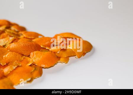 Sfocatura sfondo Natale sfocato dalle bucce di arancio e mandarino su sfondo bianco. Molti piccoli pezzi di buccia secca. Spazio di copia. Arancione Foto Stock