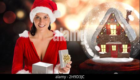 Composizione della donna felice in regalo di apertura del cappello di santa con il globo della neve sullo sfondo, spazio copia Foto Stock