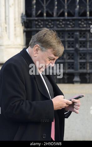 John Whittingdale MP (con: Maldon) sul suo cellulare, lasciando Palriament, dicembre 2021 Foto Stock