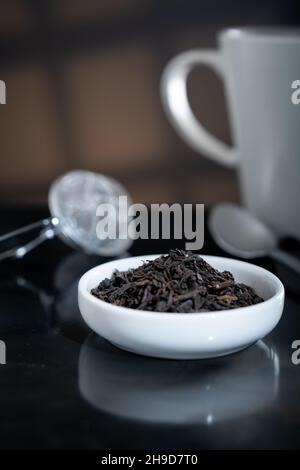 Helsinki / Finlandia - 4 DICEMBRE 2021: Primo piano selettivo di una tazza piena di foglie di tè fresco. Un filtro del tè fuori fuoco sullo sfondo. Foto Stock