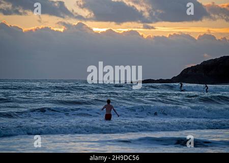 Swansea, Regno Unito. 06 dicembre 2021. Un nuotatore si avvicina al mare mentre il sole tramonta sulla Langland Bay sulla penisola di Gower, vicino Swansea questa sera. Credit: Phil Rees/Alamy Live News Foto Stock