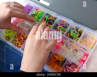 Coloratissimo arcobaleno primo apparire fasce in gomma in una scatola, mani su Foto Stock