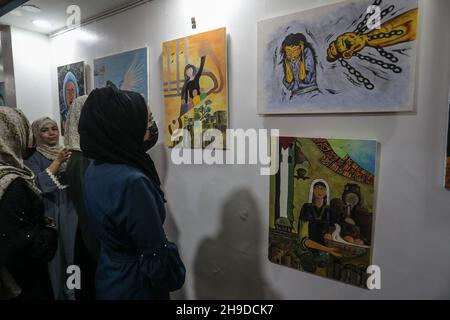 I palestinesi visitano una mostra d'arte nell'ambito di una campagna per sensibilizzare la popolazione alla violenza contro le donne, nella striscia di Gaza, il 6 dicembre 2021. Foto Stock