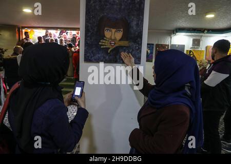 I palestinesi visitano una mostra d'arte nell'ambito di una campagna per sensibilizzare la popolazione alla violenza contro le donne, nella striscia di Gaza, il 6 dicembre 2021. Foto Stock