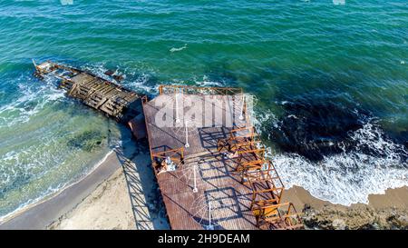 Volo aereo con vista sui droni sopra l'Old Breakwater sulla spiaggia di Sandy. Visualizzazione delle forme d'onda dall'alto Foto Stock