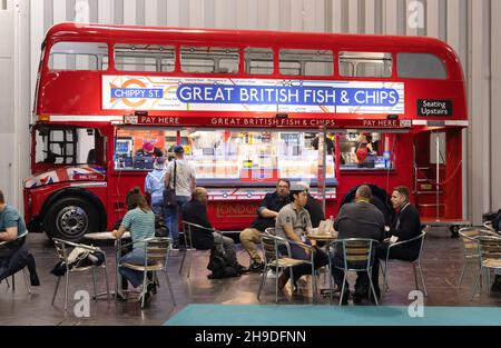 Cibo tradizionale UK; persone che mangiano pesce e patatine dal bus Great British Fish & Chips al Photography Show, NEC Birmingham UK Foto Stock
