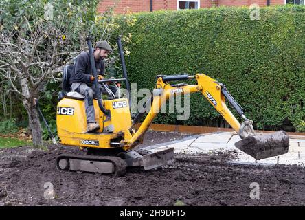 Lavoro specializzato UK; giardiniere di paesaggio UK - un uomo che opera un mini digger in un giardino domestico, Suffolk UK