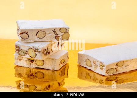 Torrone con mandorle e nocciole su uno sfondo dorato dove si riflette, copia spazio Foto Stock