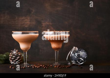 Cocktail Alexander in bicchiere da cocktail su tavolo di legno con shaker, noce moscata e piccolo grattugia con decorazioni natalizie su sfondo scuro. Fotografia delle bevande Foto Stock