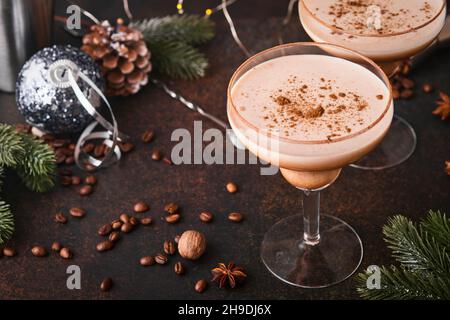 Cocktail Alexander in bicchiere da cocktail su tavolo di legno con shaker, noce moscata e piccolo grattugia con decorazioni natalizie su sfondo scuro. Fotografia delle bevande Foto Stock