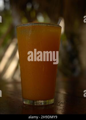 La foto mostra il succo di frutta passione. Foto scattata al bar su un'isola caraibica. La spiaggia e la linea dell'oceano sono visibili sullo sfondo. Rinfreschi ar Foto Stock