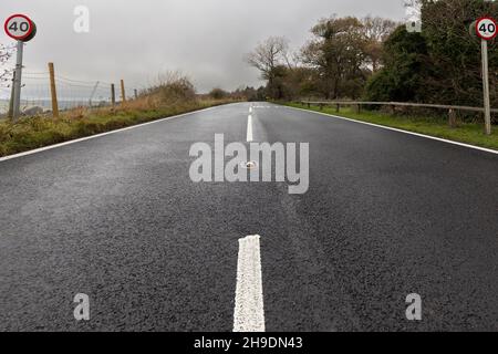Un angolo basso di una strada nella contea inglese del Kent. Sono visibili due segnali di limite di velocità di 40 miglia all'ora. Le linee bianche entrano nella distanza. Foto Stock