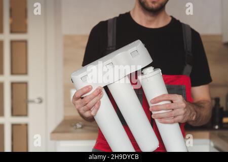 Idraulico in cucina che tiene la casa a tre stadi fiasca sistema di purificazione dell'acqua Foto Stock