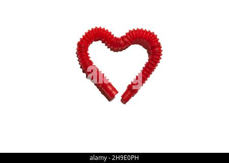 Steso rosso pop it tubo bambini giocattolo piegato a forma di cuore. Giocattolo antistress in plastica tagliato fuori con la sua ombra dura su sfondo bianco. Isolare Foto Stock