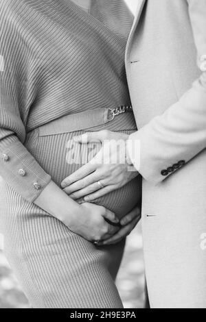 Primo piano in scala di grigi di una donna incinta con un uomo che abbraccia Foto Stock