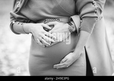 Primo piano in scala di grigi di una donna incinta con un uomo che abbraccia Foto Stock