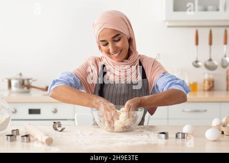 Felice giovane musulmana donna che indossa Hijab e Apron cottura in cucina Foto Stock
