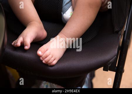 Primo piano dei piedi di un bambino seduto nel passeggino Foto Stock