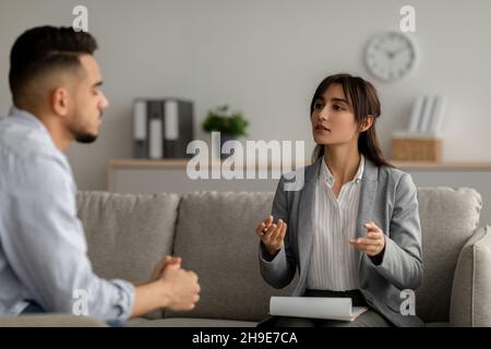 Concetto di salute mentale. Ragazzo arabo che parla allo psicologo, ascolta consigli e spiega il suo problema Foto Stock