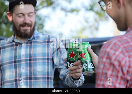 KHARKOV, UCRAINA - 31 LUGLIO 2021: Lattine di Heineken birra lager pallido nelle mani degli uomini all'aperto Foto Stock