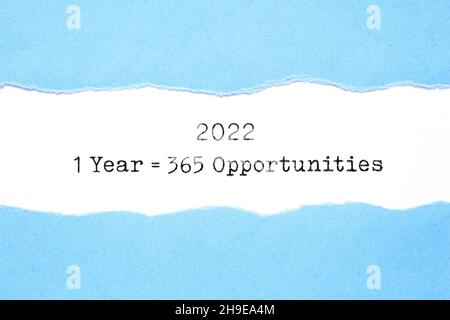 Messaggio di ispirazione 1 anno 2022 pari a 365 opportunità che appaiono dietro carta blu strappata tipizzata su foglio bianco. Foto Stock