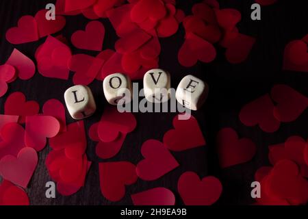 La parola AMORE da cubi di legno su legno scuro. San Valentino sfondo Foto Stock